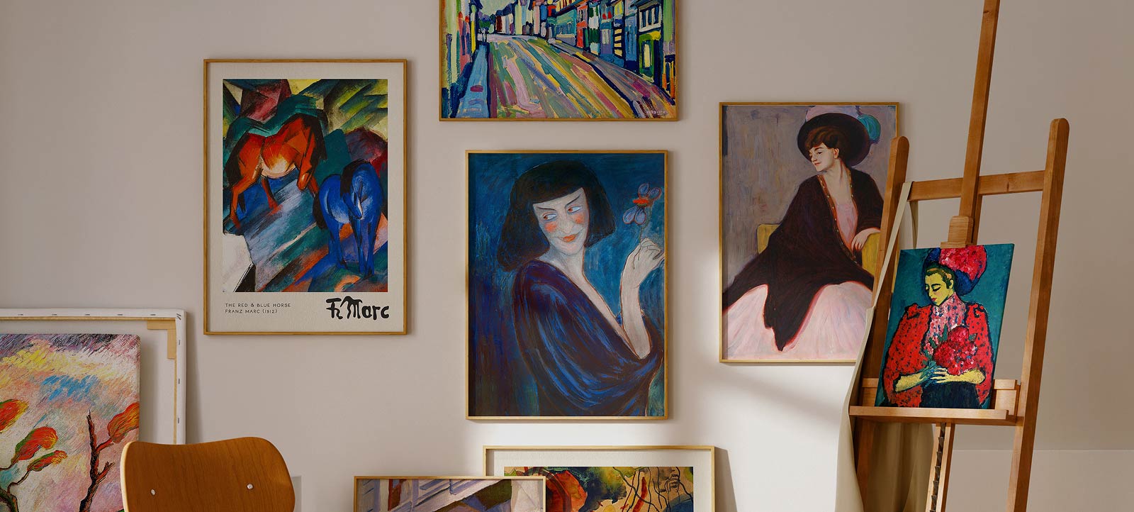 Gerahmte Wandbilder, daneben eine Staffelei mit Bild