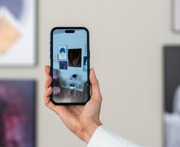 Hand holding a smartphone with an AR view of a gallery wall featuring modern art posters