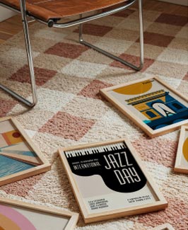 Gerahmte Kunstdrucke auf Teppichboden neben einem Stuhl