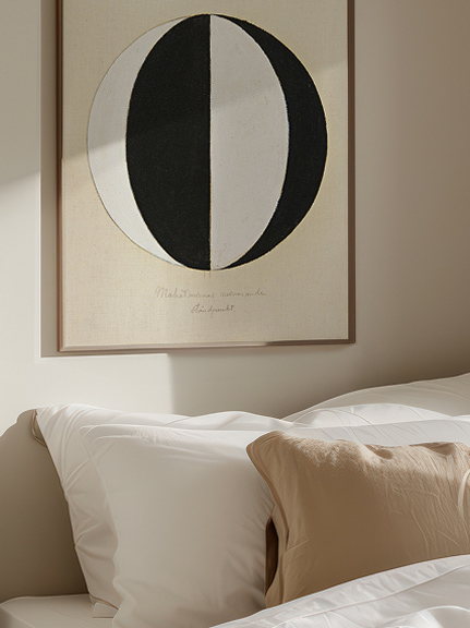 Bett mit Kissen unter einem Wandbild in Schwarz-Weiß