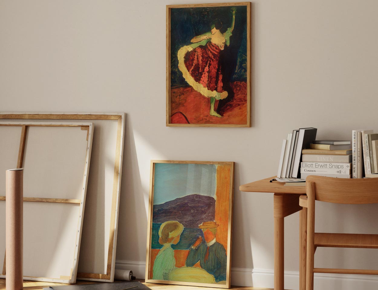 Zwei gerahmte Gemälde mit Figuren stehen an einer Wand, daneben ein Tisch mit Büchern