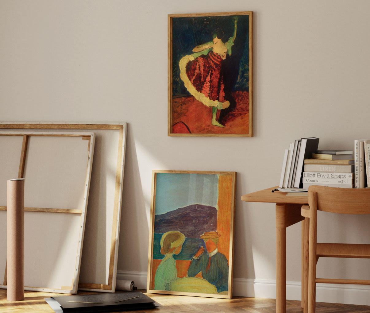 Zwei gerahmte Gemälde mit Figuren stehen an einer Wand, daneben ein Tisch mit Büchern