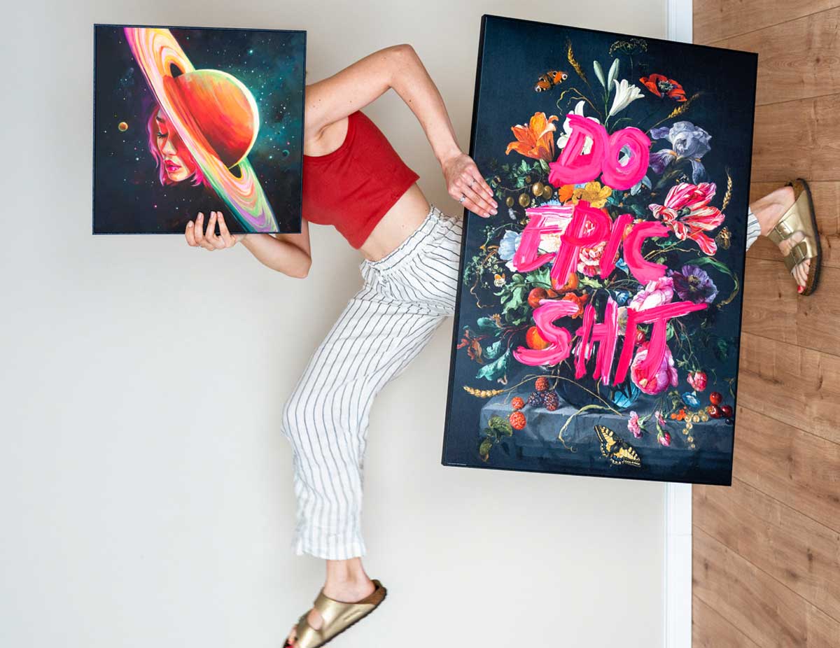 A person carrying two colourful wall art prints
