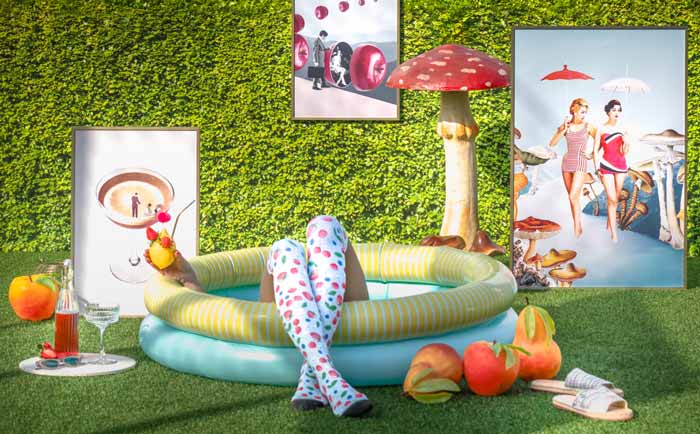 Creative summer scene with a paddling pool, cocktail, vibrant art prints and decorative mushrooms on a grassy lawn